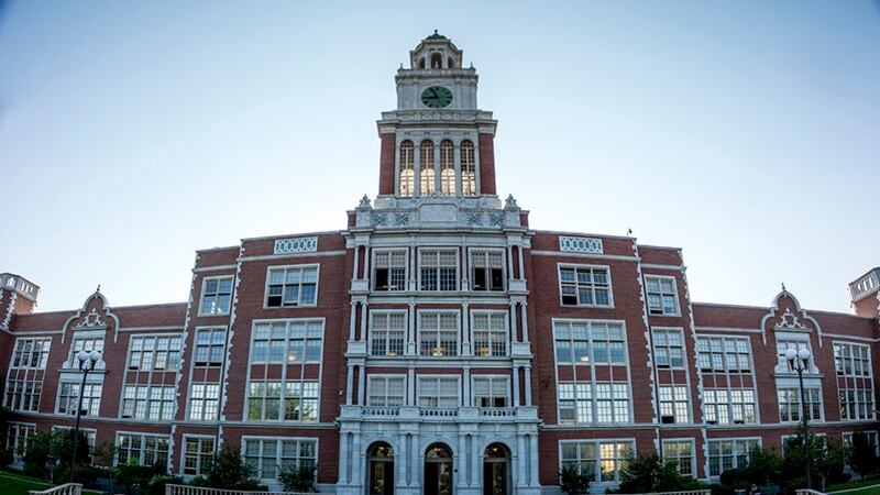 The outside of East High School. It is a stately brick building with lots of windows and a clocktower.