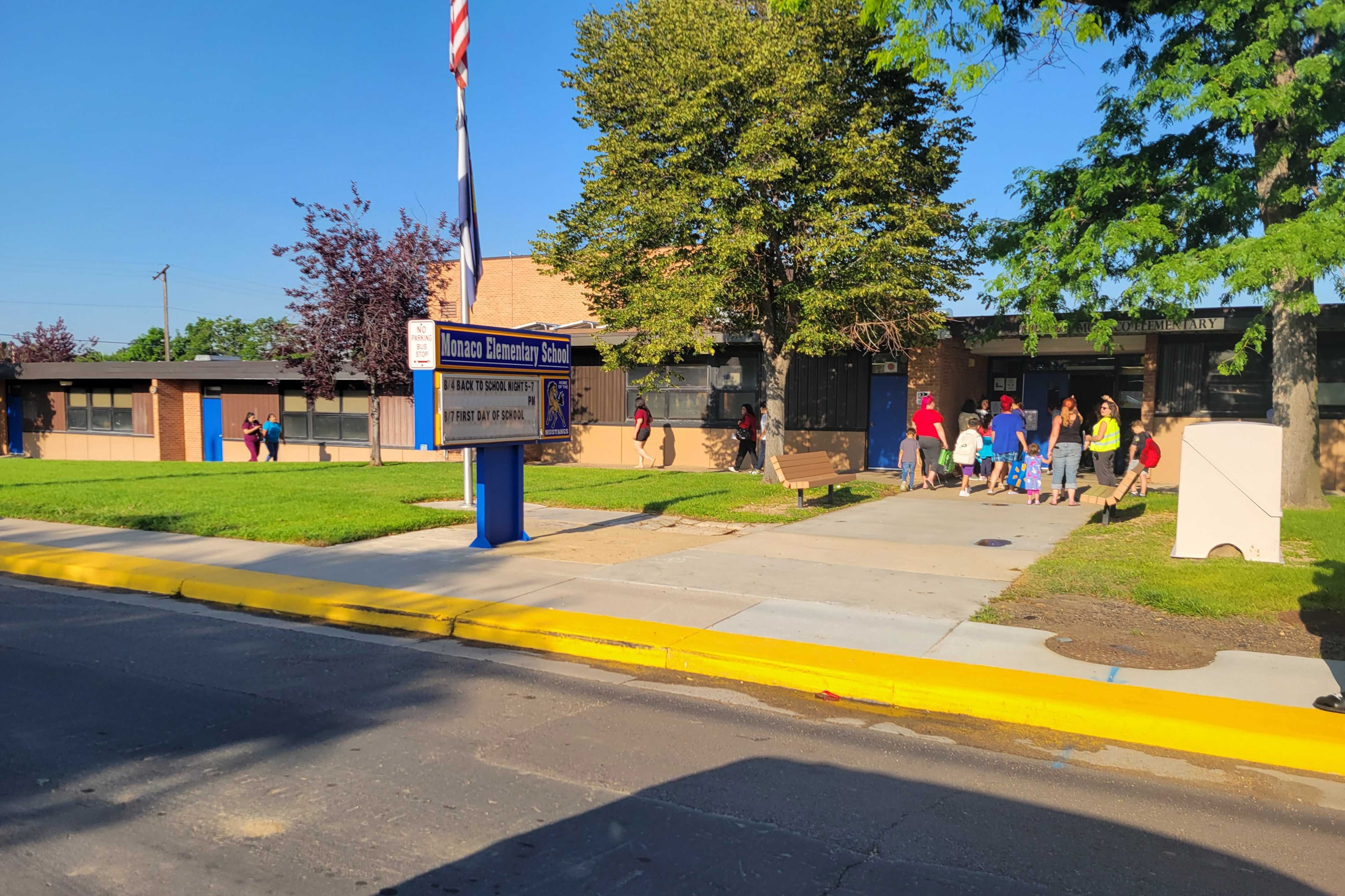 Students stand outside a school building.