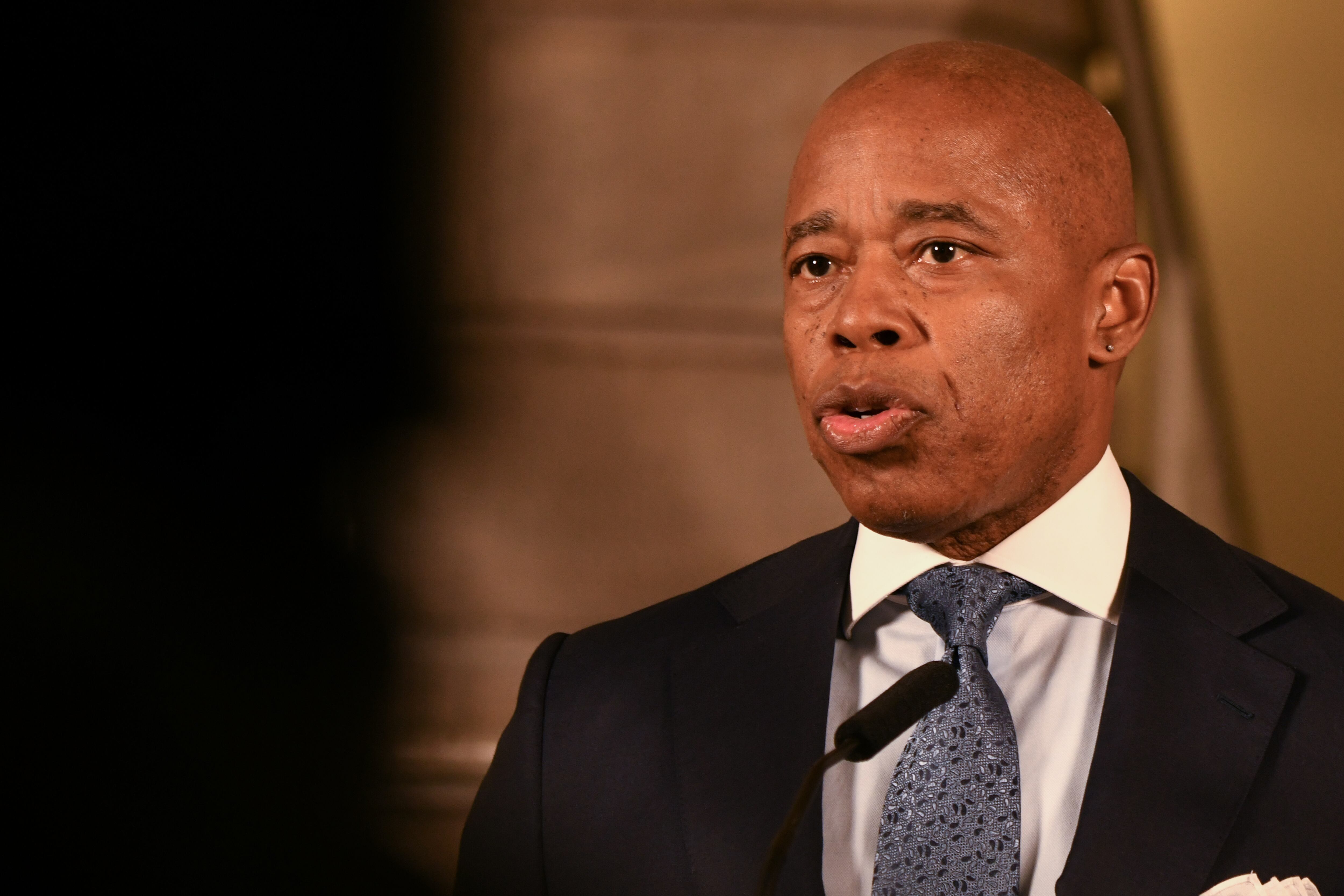 A close up of a man in a dark suit jacket with a white shirt and blue tie