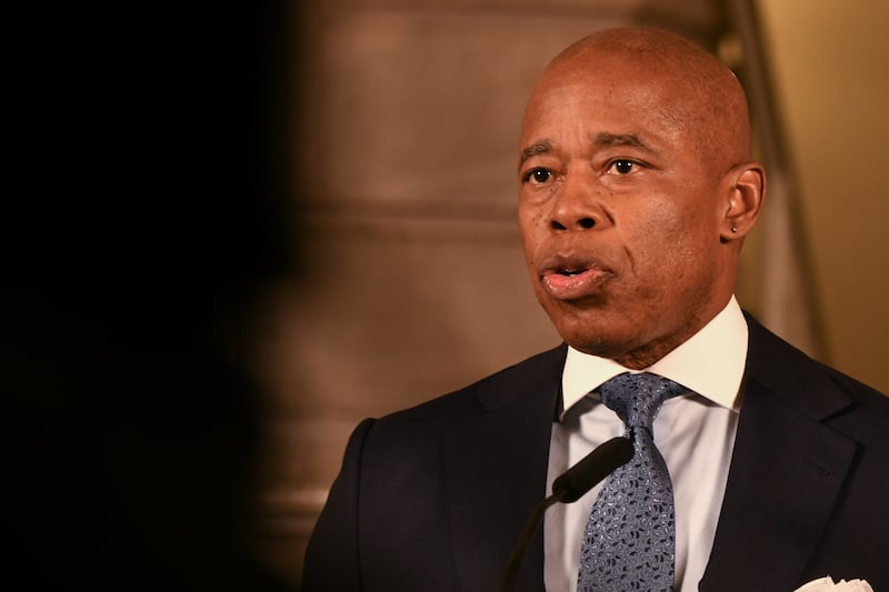 A close up of a man in a dark suit jacket with a white shirt and blue tie
