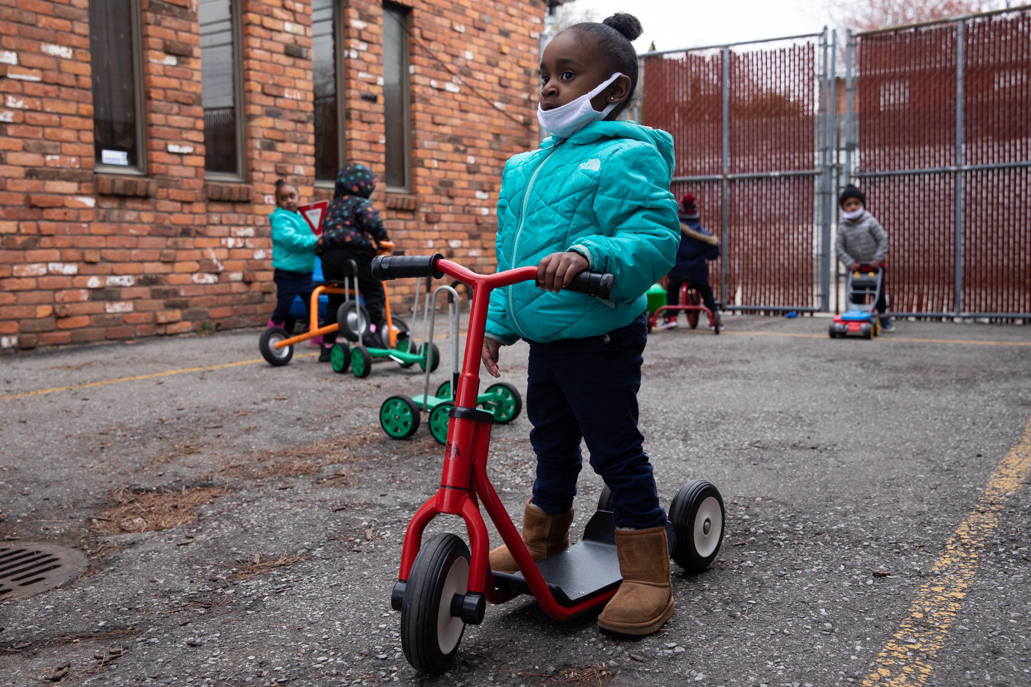Payton Watson (front) rides around on a scooter as the preschoolers play outside at Little Scholars child care center in Detroit, Michigan, U.S., on Thursday April 1, 2021.