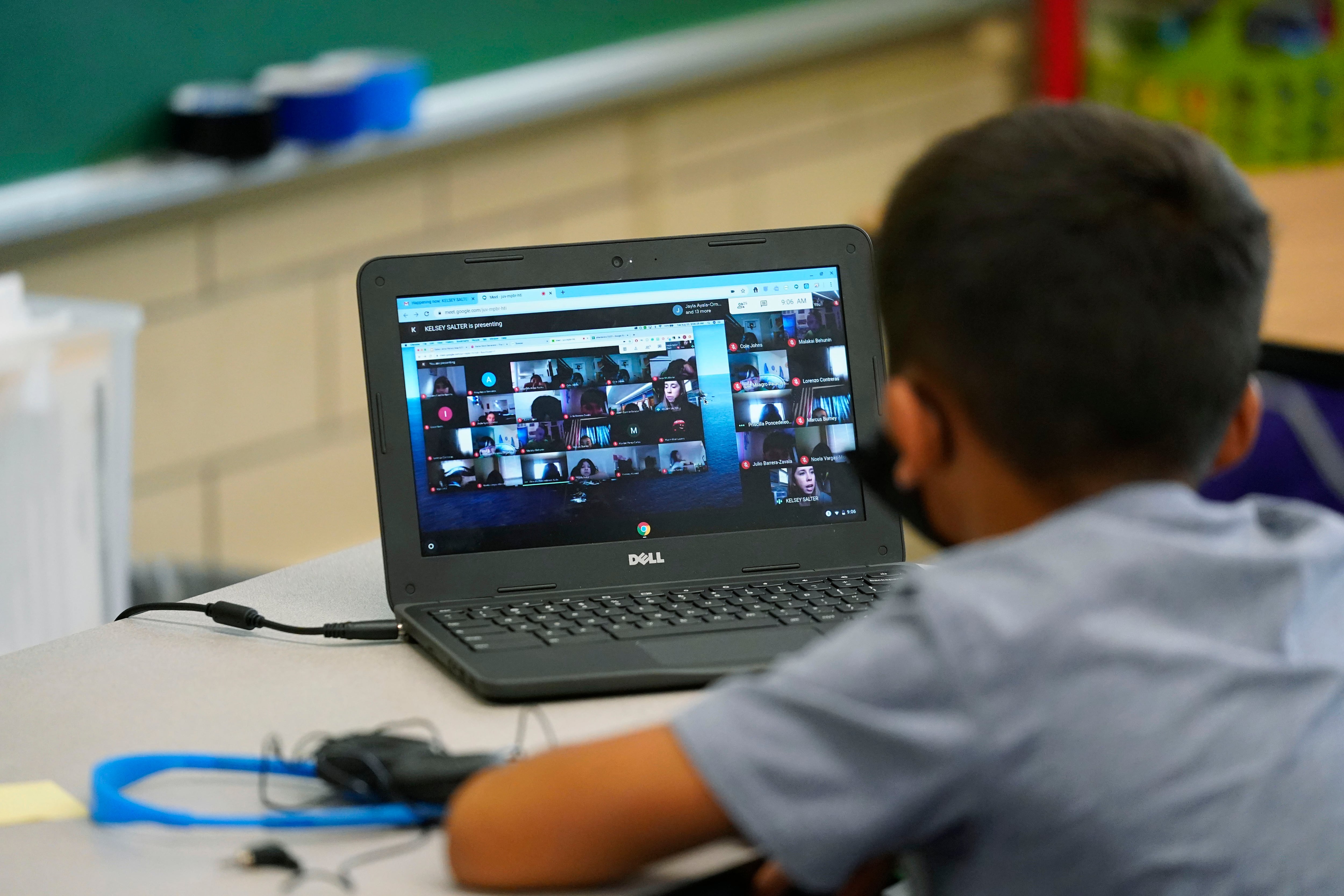 Boy participates in a video lesson on his laptop in a learning center.