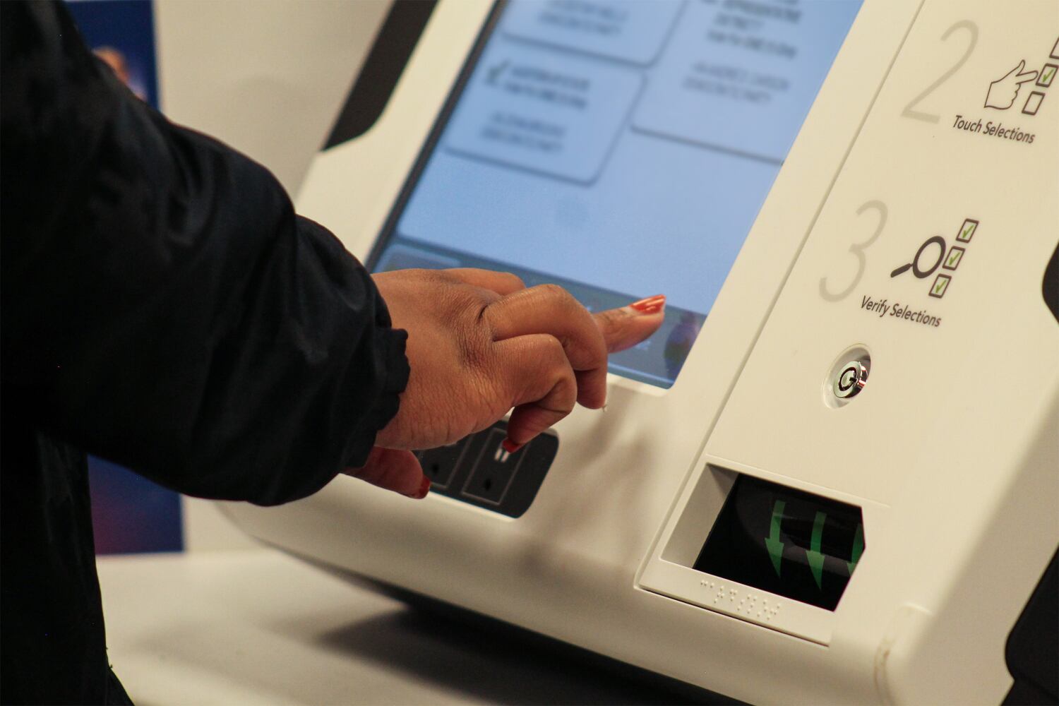 a hand selects candidates on voting machine