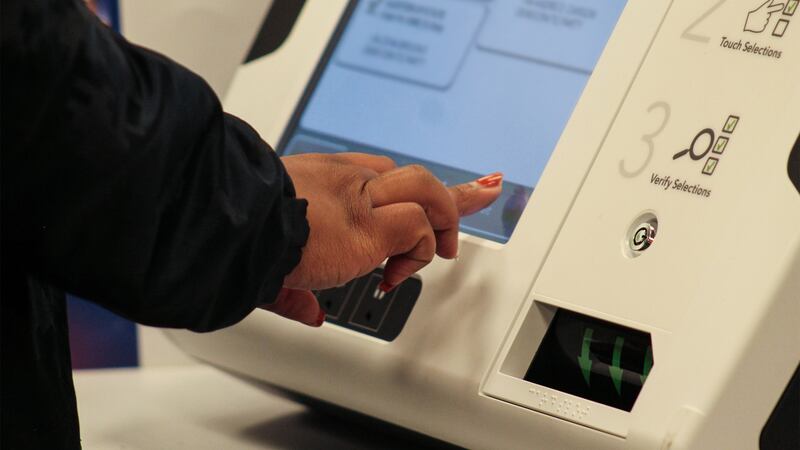 a hand selects candidates on voting machine