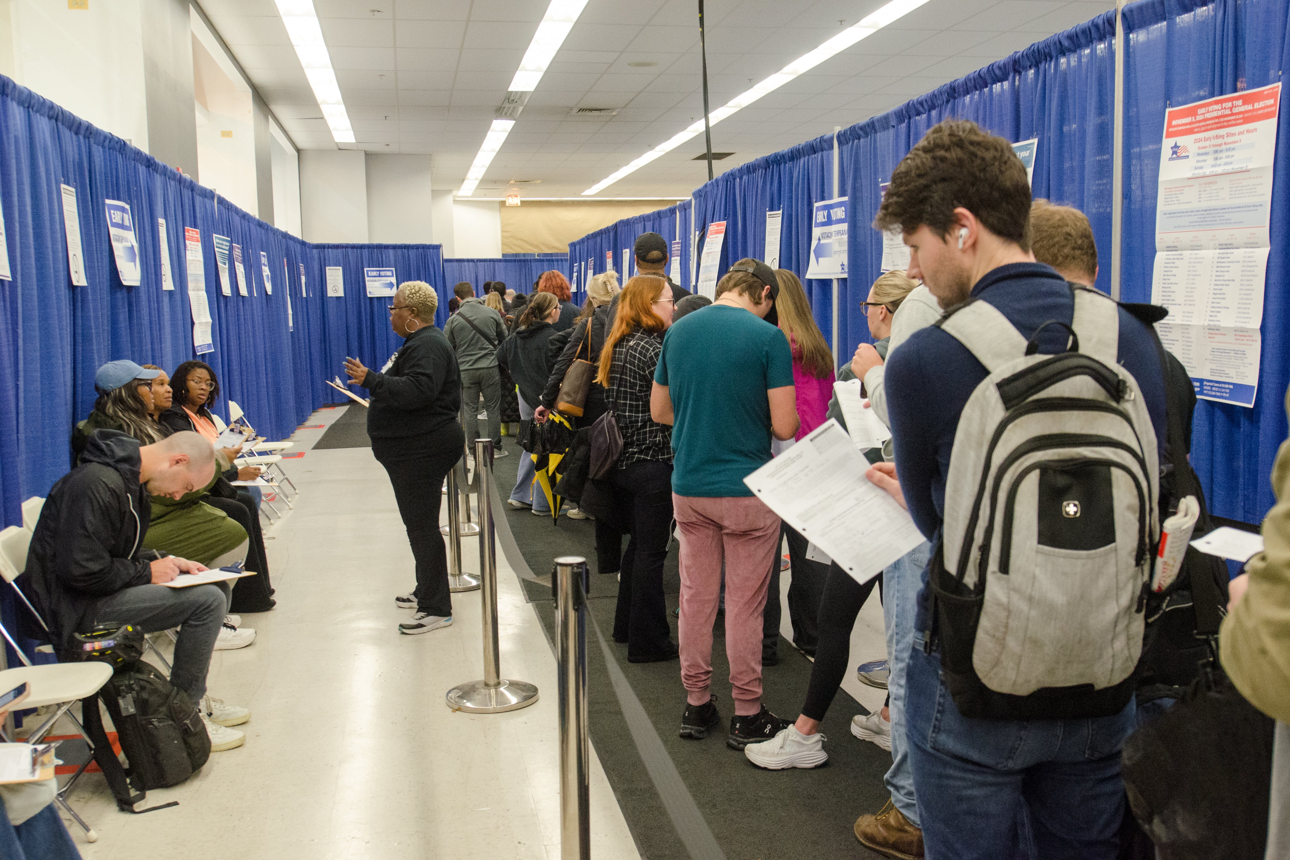 A photograph of a line of people waiting to vote inside of a polling station.