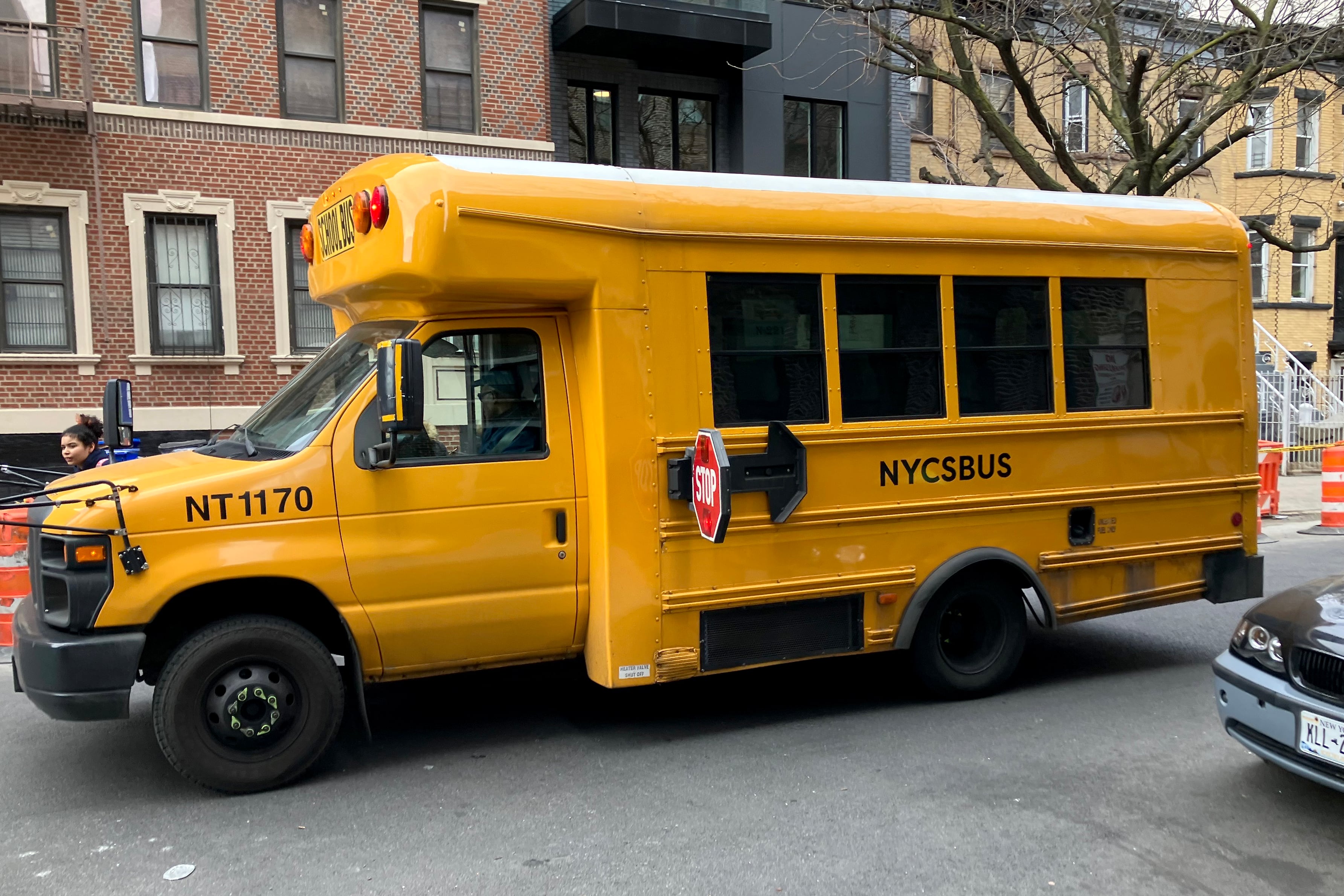 A short yellow bus is parked on a street outside.