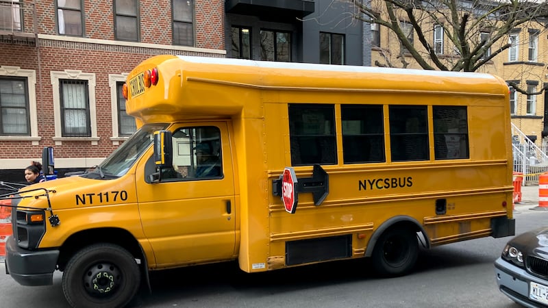 A short yellow bus is parked on a street outside.