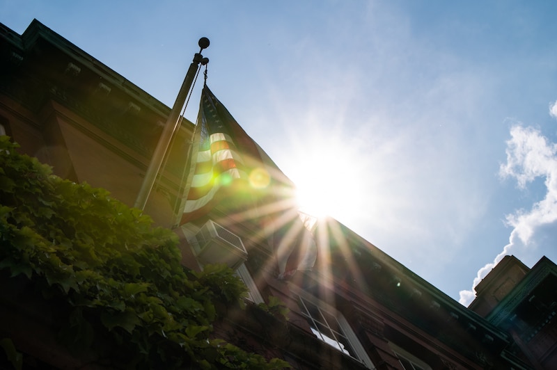 A sunbeam near an American flag outside of a school building.