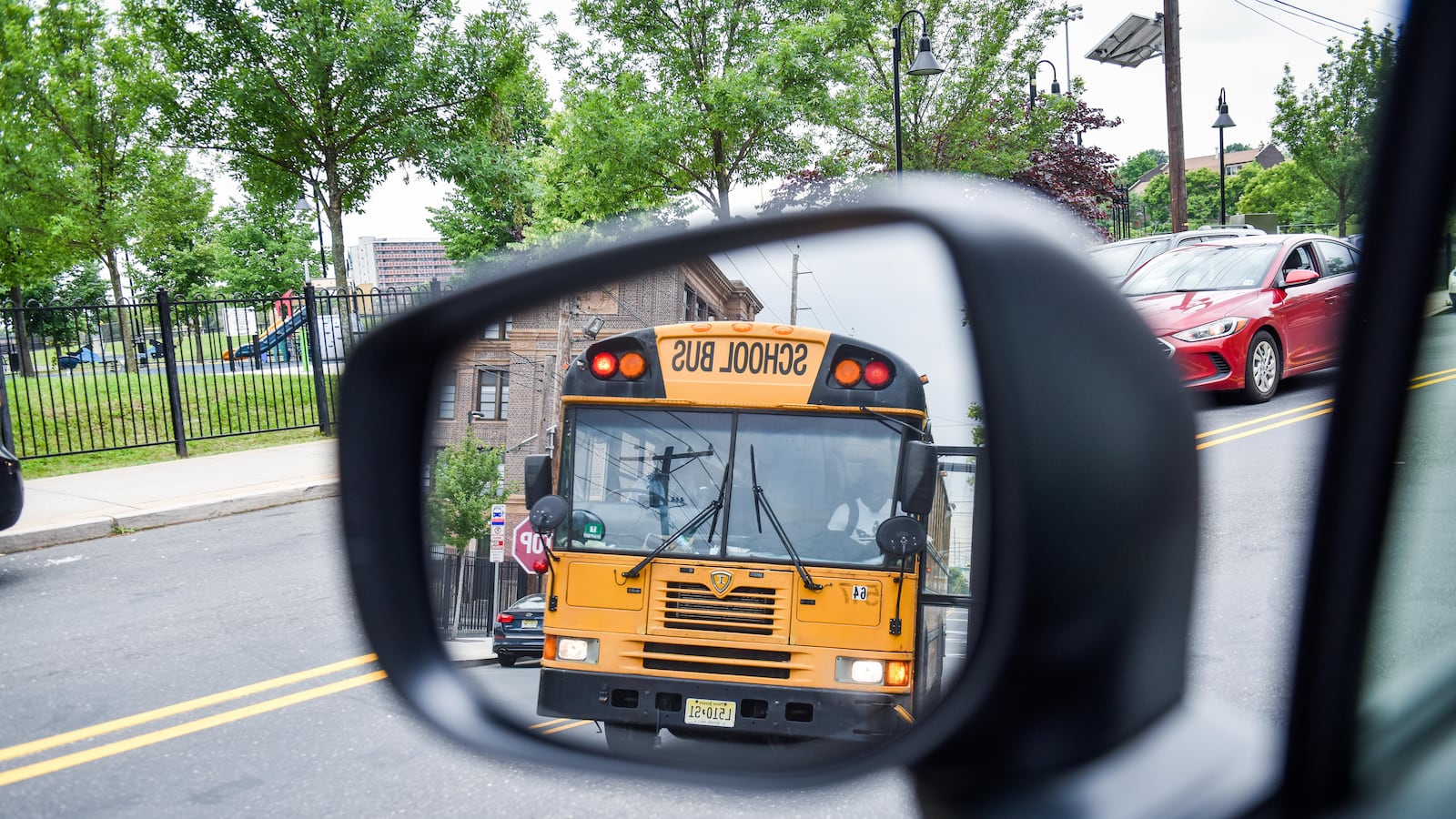 A yellow school bus is reflected in a rearview mirror as they drive down the road.