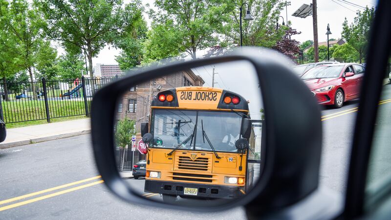 A yellow school bus is reflected in a rearview mirror as they drive down the road.