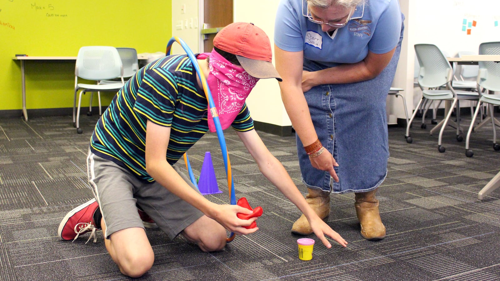 A student forms their first name initial with Play-Doh while holding a hula hoop. The teacher guided him through a series of tasks while blindfolded as part of a game that was meant to teach trust.