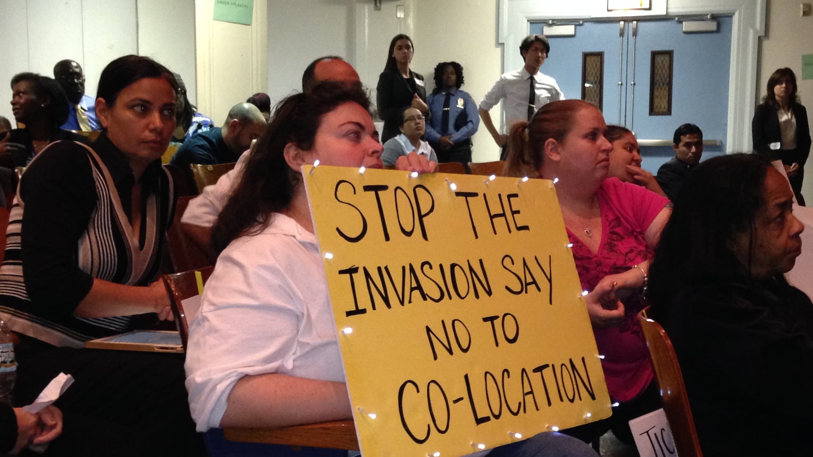 The president of a community education council in Brooklyn holds a sign opposing new co-locations at a Panel for Educational Policy meeting in October 2013.