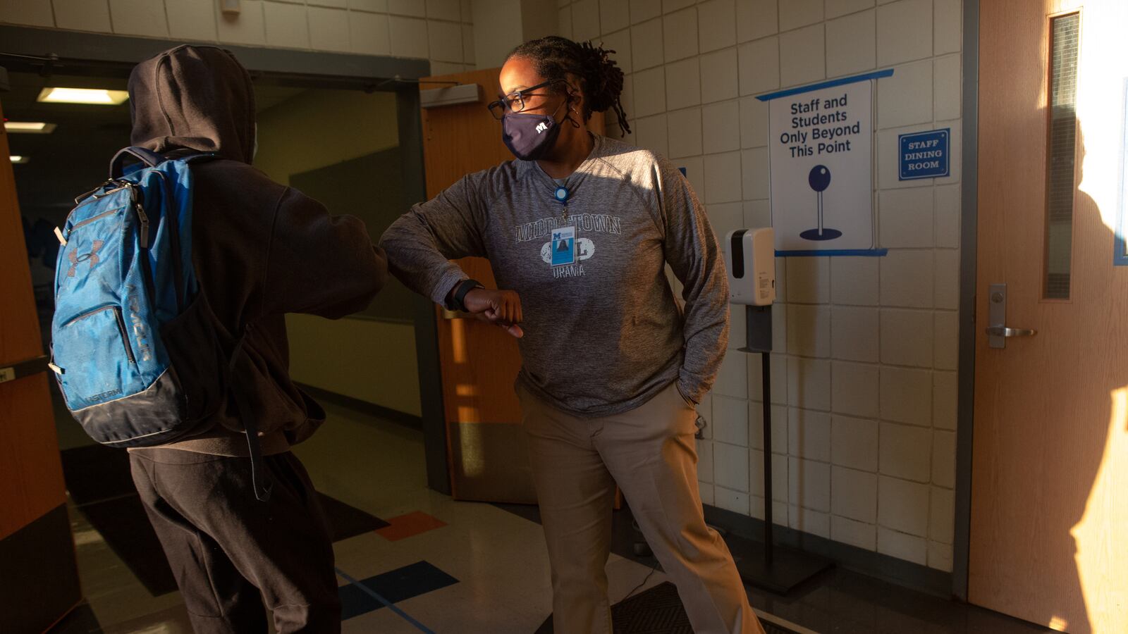 Staff member Charlene Shepard welcomes students and monitors a thermal temperature scanner at an entrance to Middletown High School.