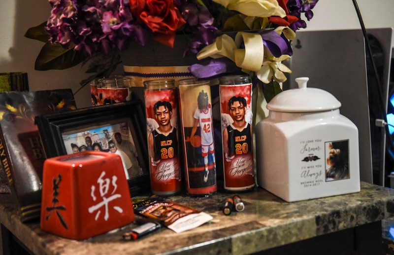 Memorial candles and items sit on a marble shelf.