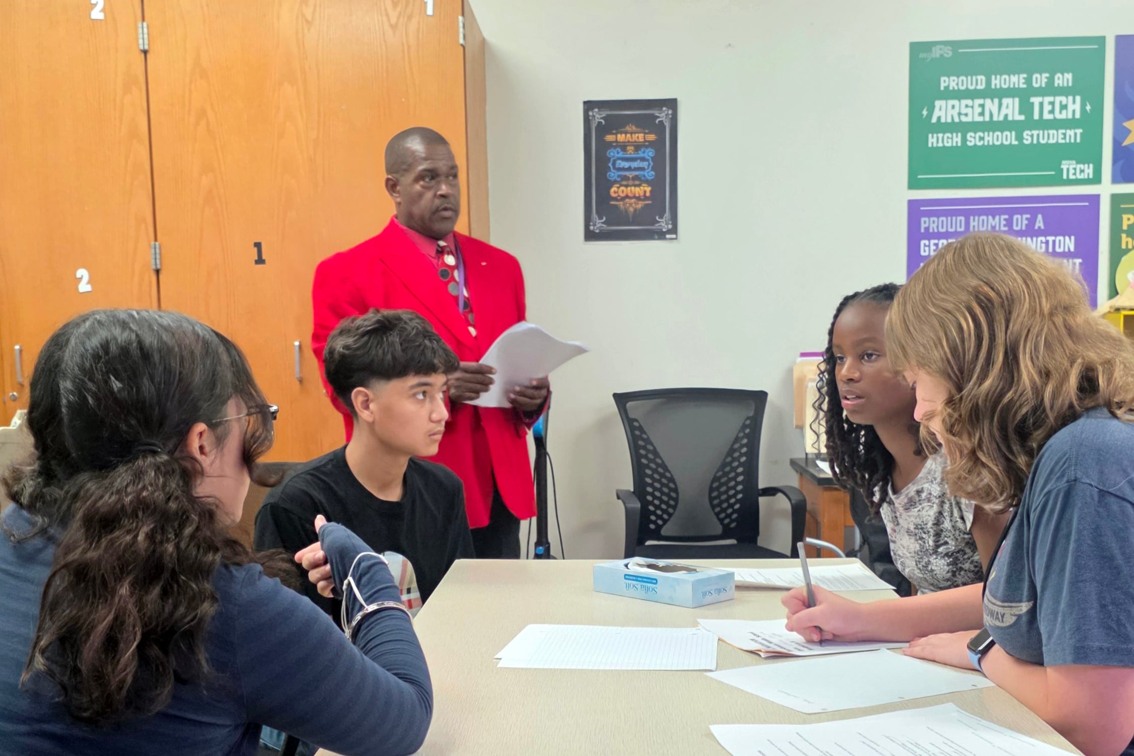 Four students and one adult in a classroom.
