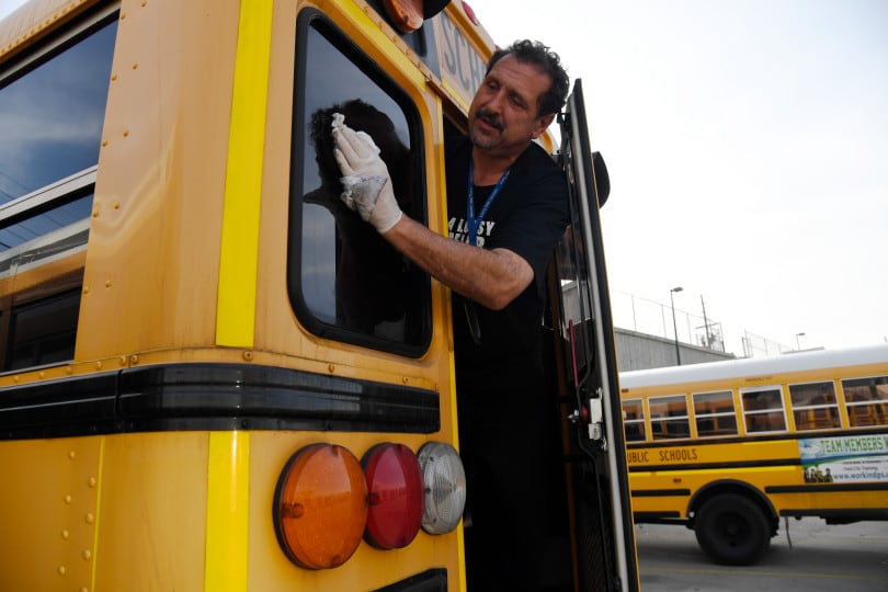 Paraprofessional Ben Johnson washes of the back window of a bus at the Denver Public Schools Hilltop Terminal November 10, 2017.