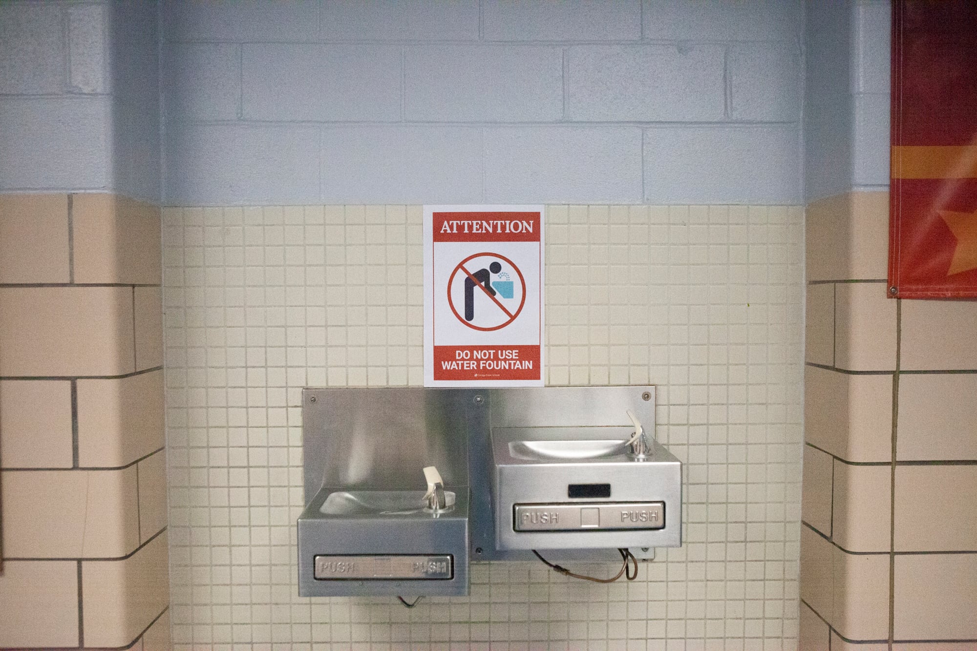 A sign between two water fountains that reads: Attention. Do not use water fountain.