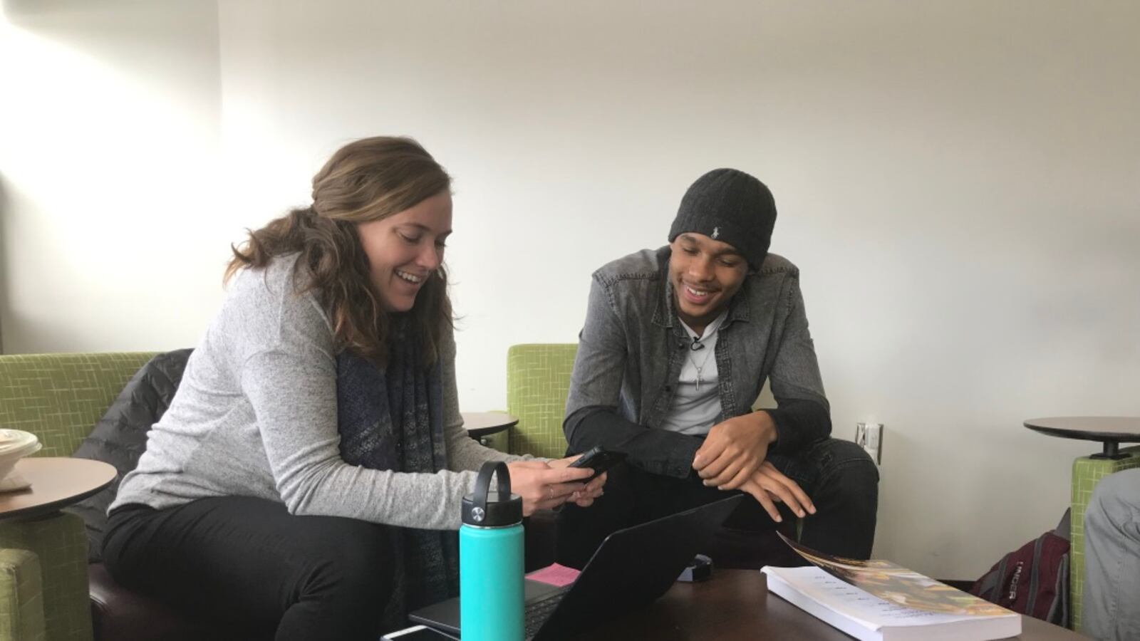 Katherine "Kat" Grow, the alumni success coordinator at the Jalen Rose Leadership Academy, uses the cell phone of Demetrius Robinson, an alum of the school now in his freshman year at Central Michigan University, to check his grades.