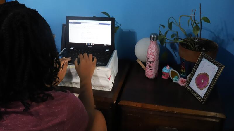 A student works at a laptop in her room.