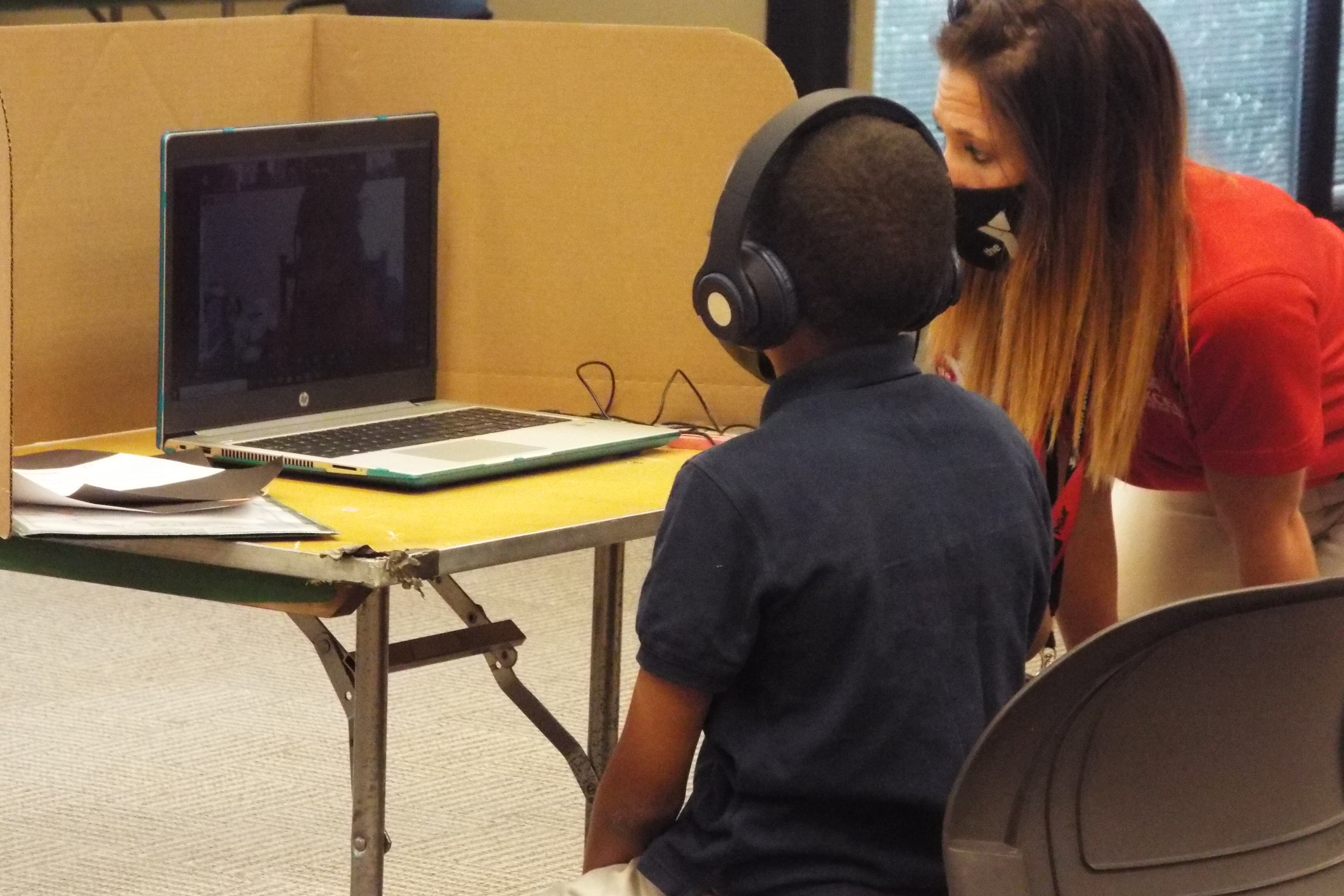 A Shelby County Schools student gets assistance from a staffer as he works remotely from the YMCA’s virtual learning center in Cordova on the first day of school.
