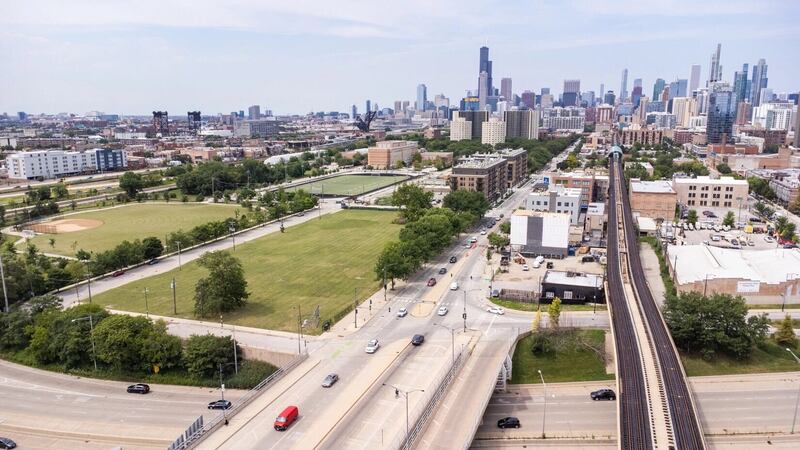 Overhead view of vacant lot with highways and roads in the foreground and the Chicago skyline in the background.