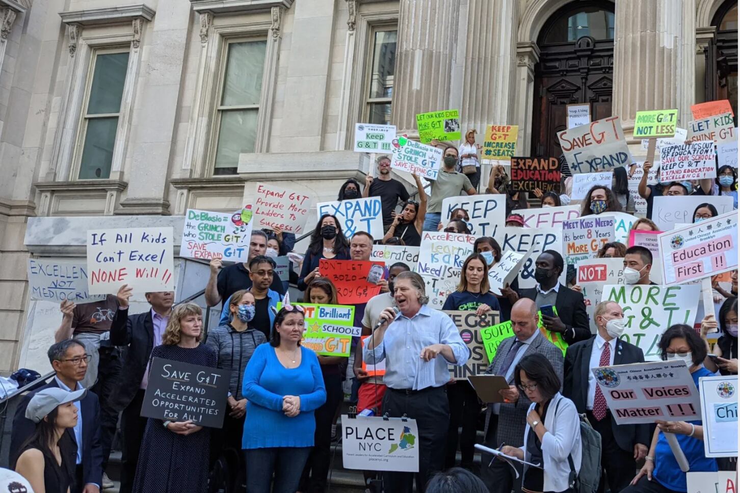 Students and parents hold signs on the steps at the Department of Education’s Lower Manhattan headquarters to expand the Gifted & Talented program. Oct. 14, 2021.