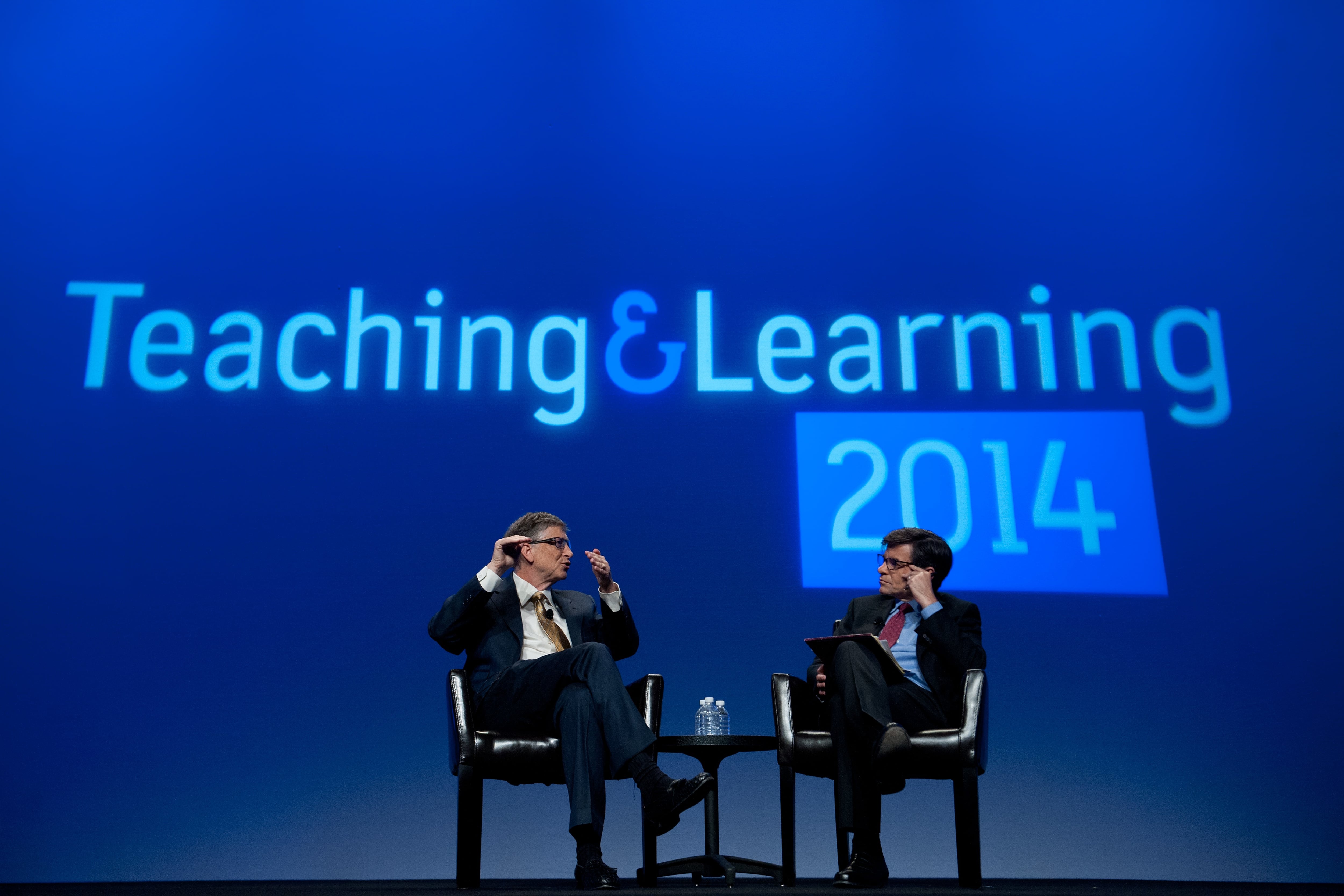 (Left to right) Microsoft founder Bill Gates and television host George Stephanopoulos sit face-to-face on stage during an interview in front of a blue projected backdrop that reads “Teaching &amp; Learning 2014”.
