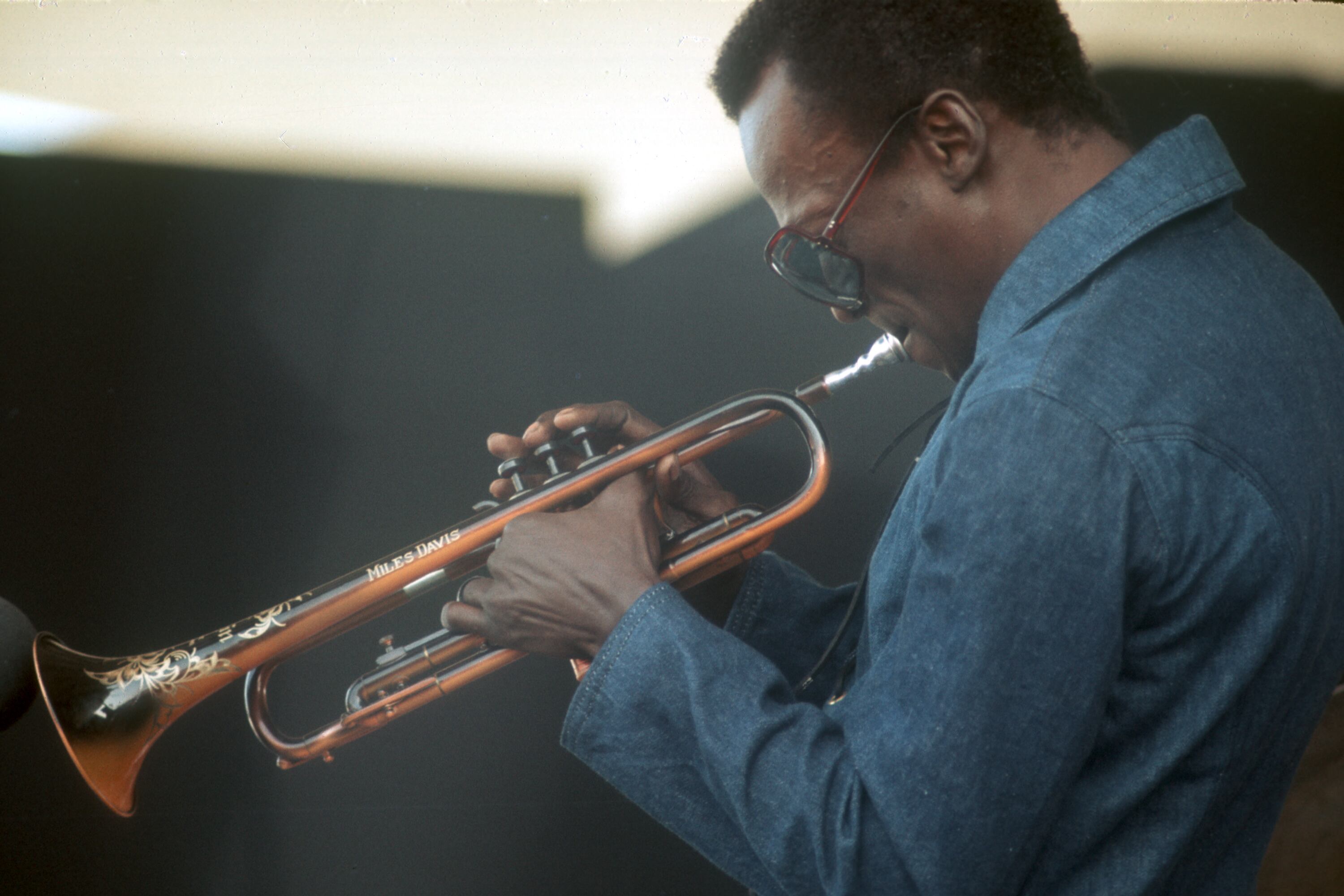 Miles Davis plays a trumpet with his name etched on the side.