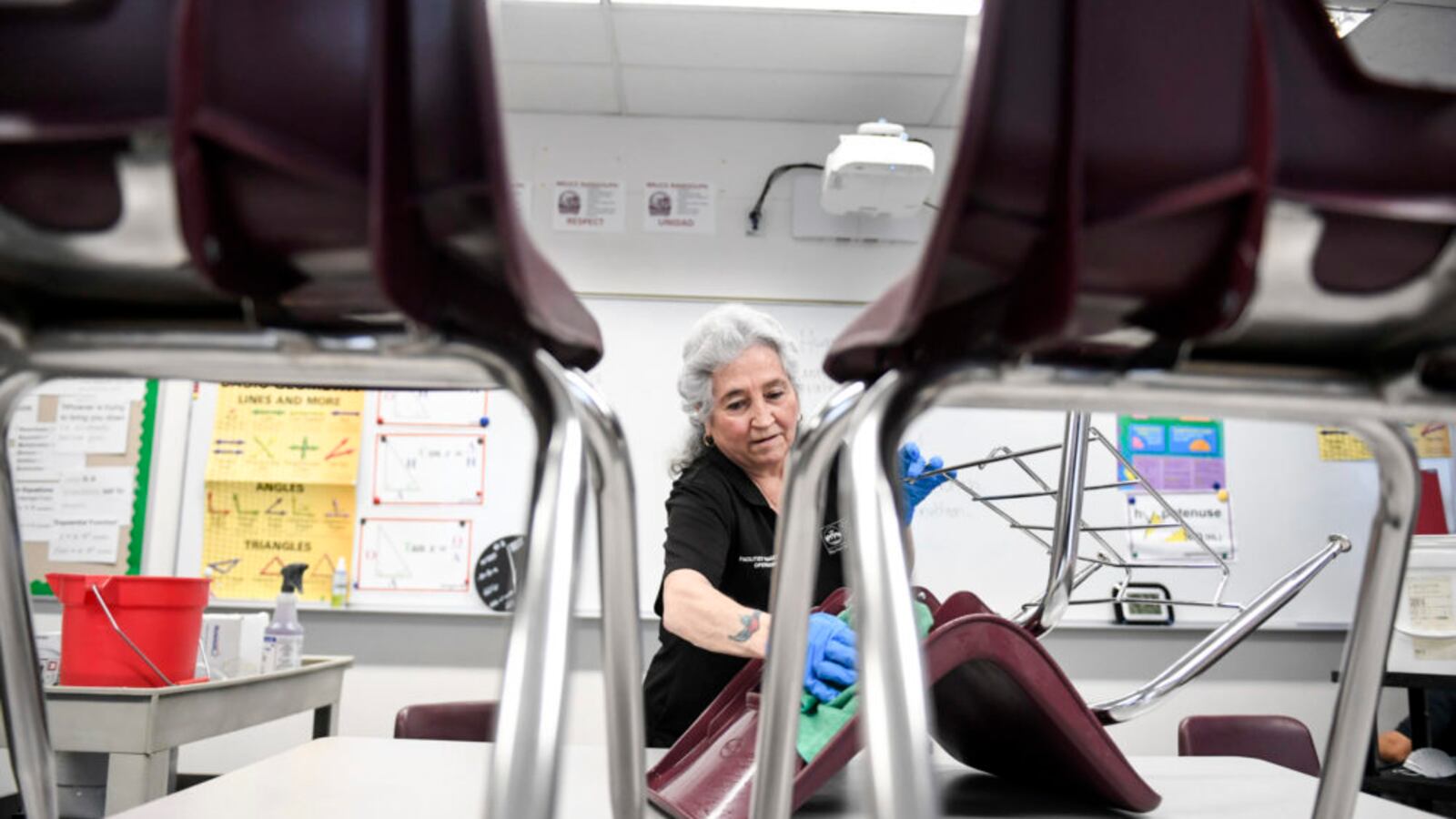 Lenora Vallejos cleans chairs at Bruce Randolph School in Denver on Thursday, March 19, 2020.
