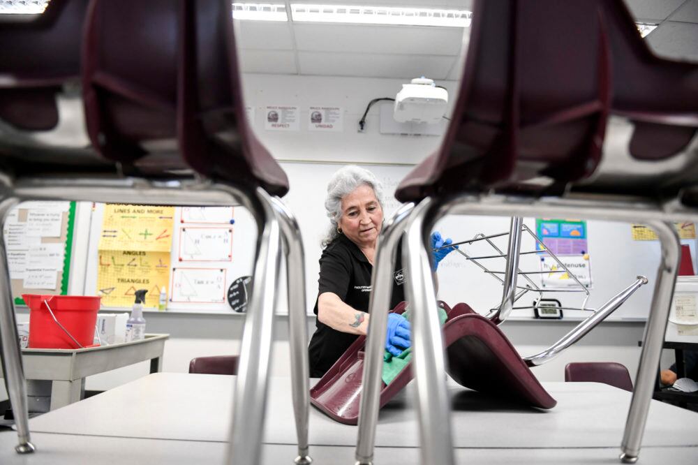 Lenora Vallejos cleans chairs at Bruce Randolph School in Denver on Thursday, March 19, 2020.