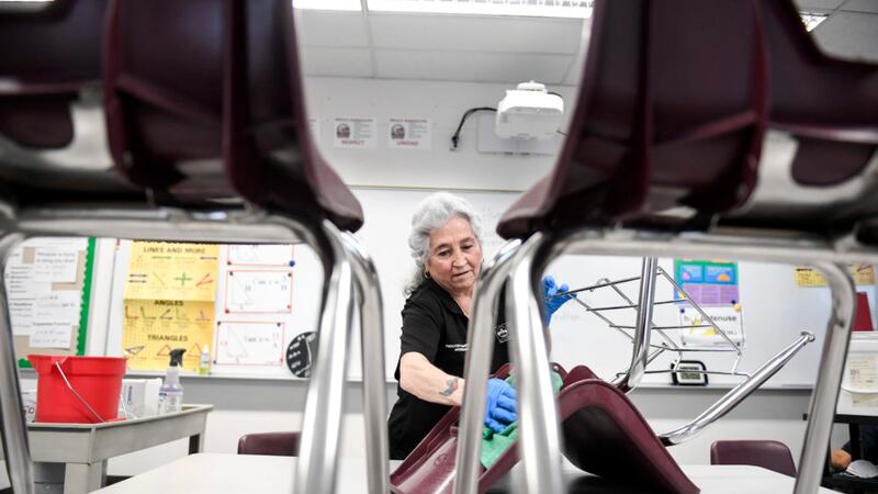 Lenora Vallejos cleans chairs at Bruce Randolph School in Denver on Thursday, March 19, 2020.