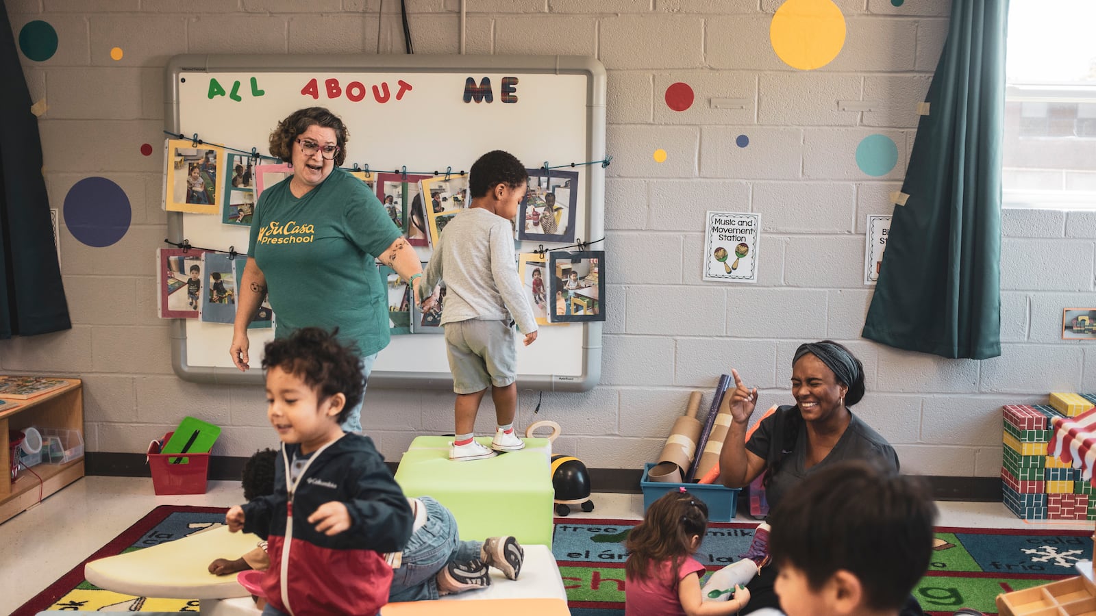 Two women teachers interact with four preschool students in their classroom