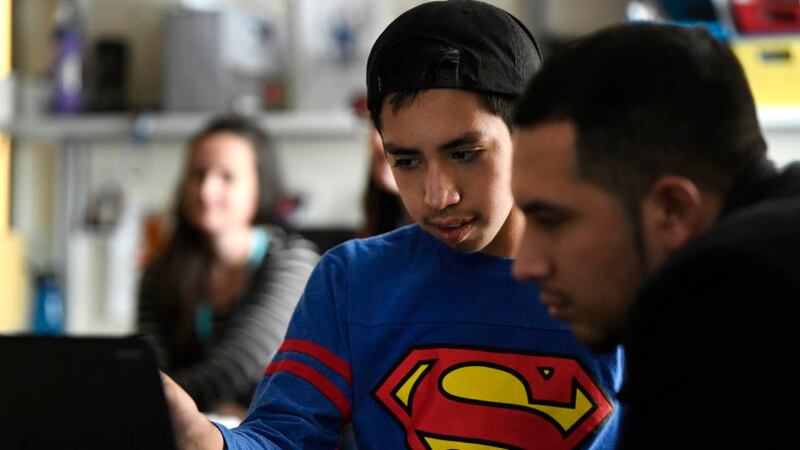 Josue Bonilla, 13, middle, works on the computer with his older brother Daniel, 23, right, who came to visit Josue in his special education class at Strive Prep on December 20, 2016 in Denver, Colorado.