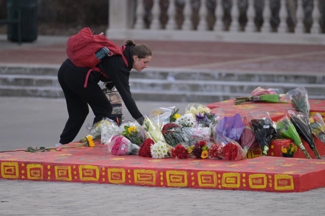 A high school student lays a bouquet of flowers outside of Denver’s East High School.