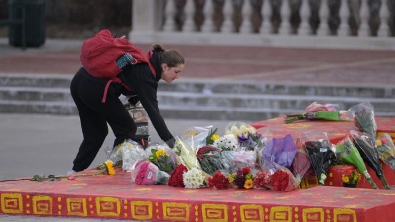 A high school student lays a bouquet of flowers outside of Denver’s East High School.