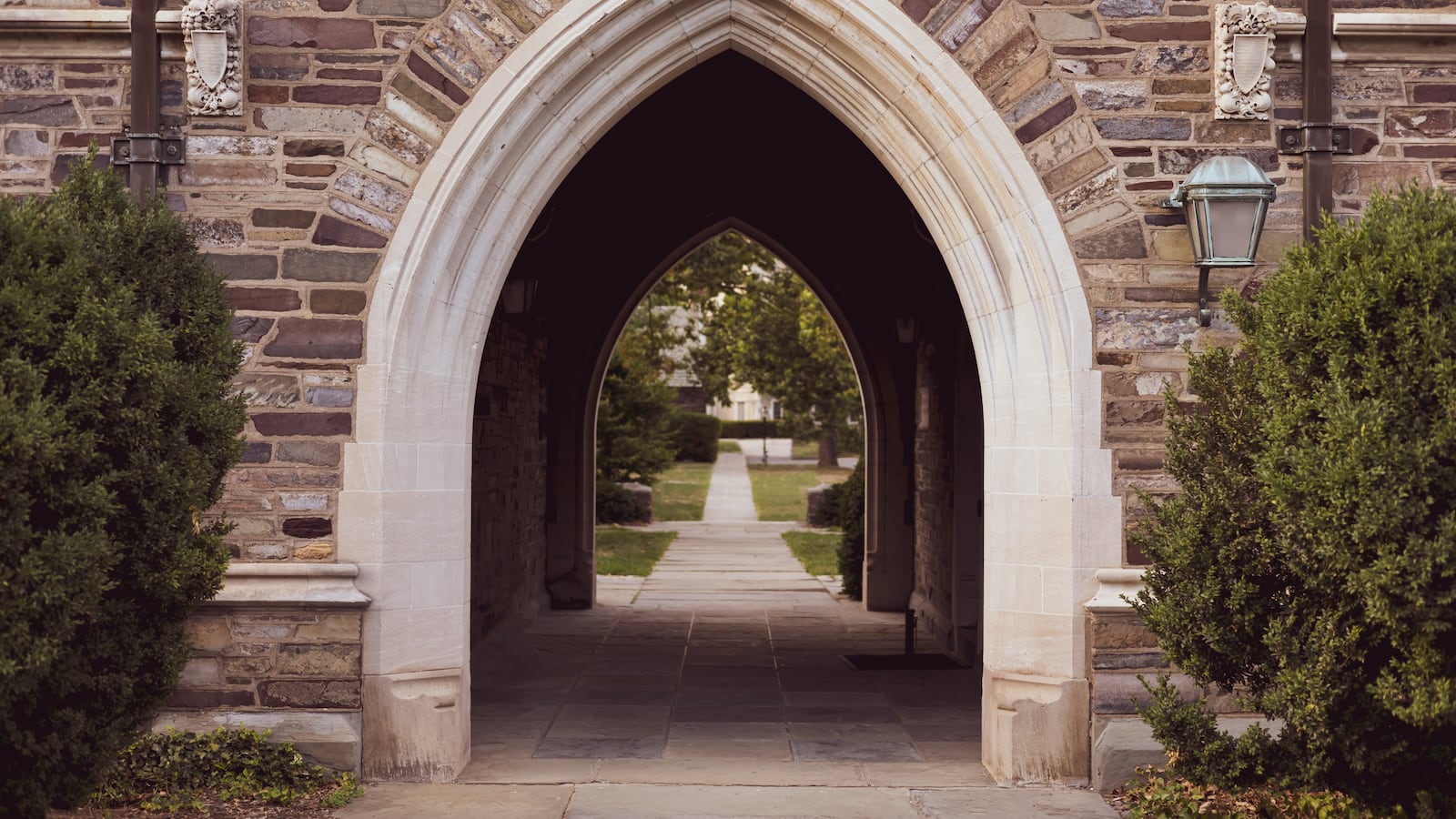An stone archway tunnel passage on gothic-style college campus.