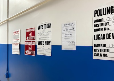 A white and blue wall with voting information taped on.
