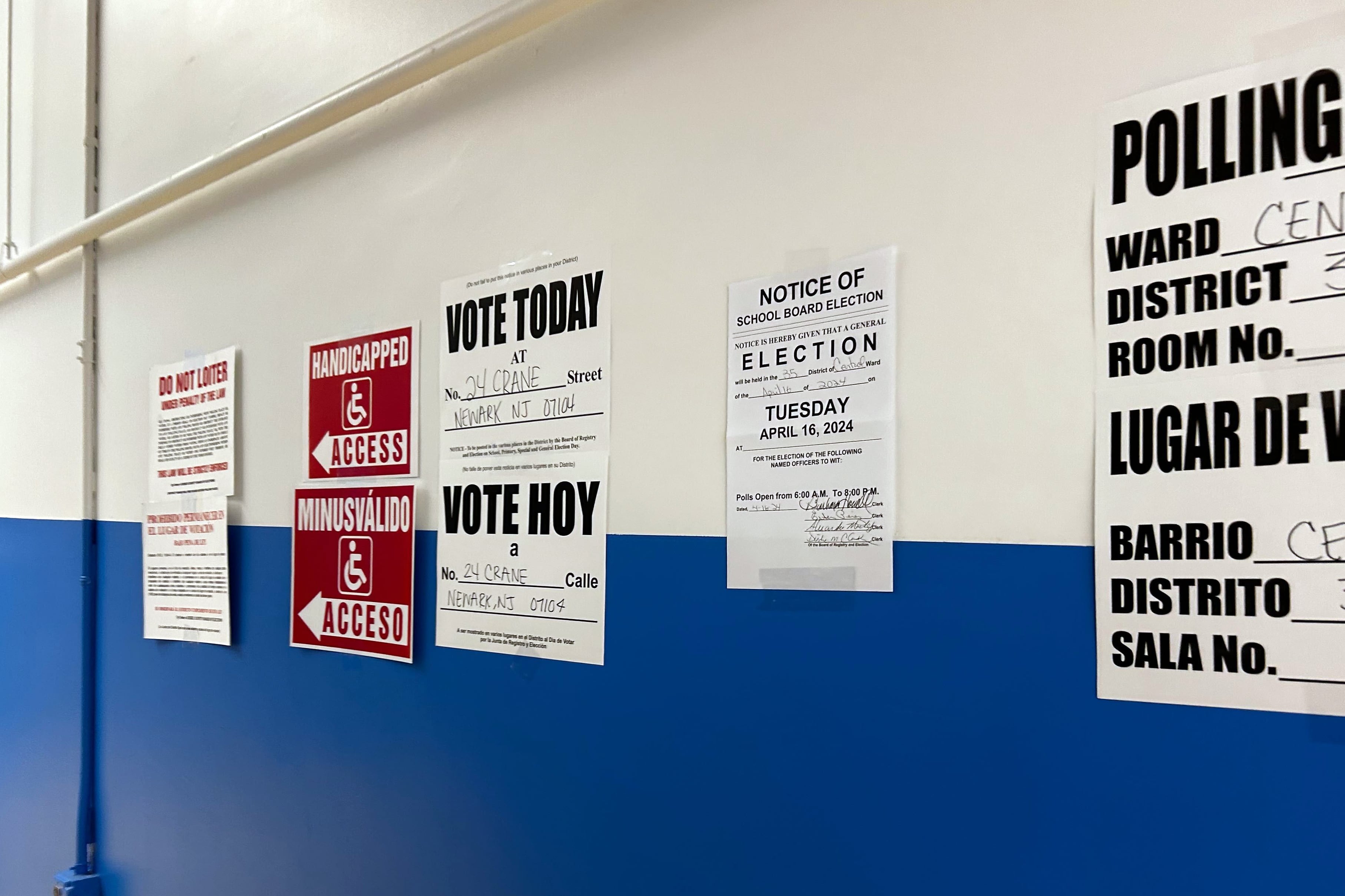 A white and blue wall with voting information taped on.