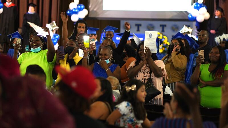 A sea of excited family members cheer on their loved ones from their seats at a graduation ceremony.