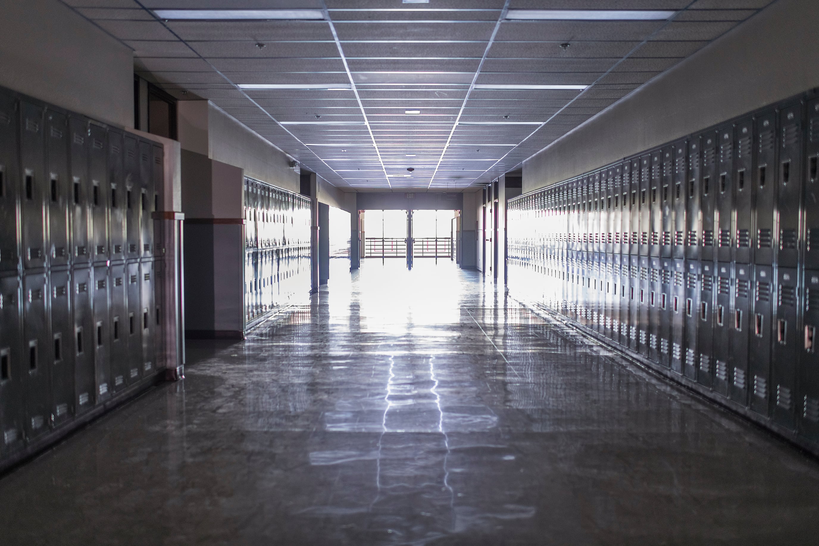 Empty high school corridor with lockers lining the walls.