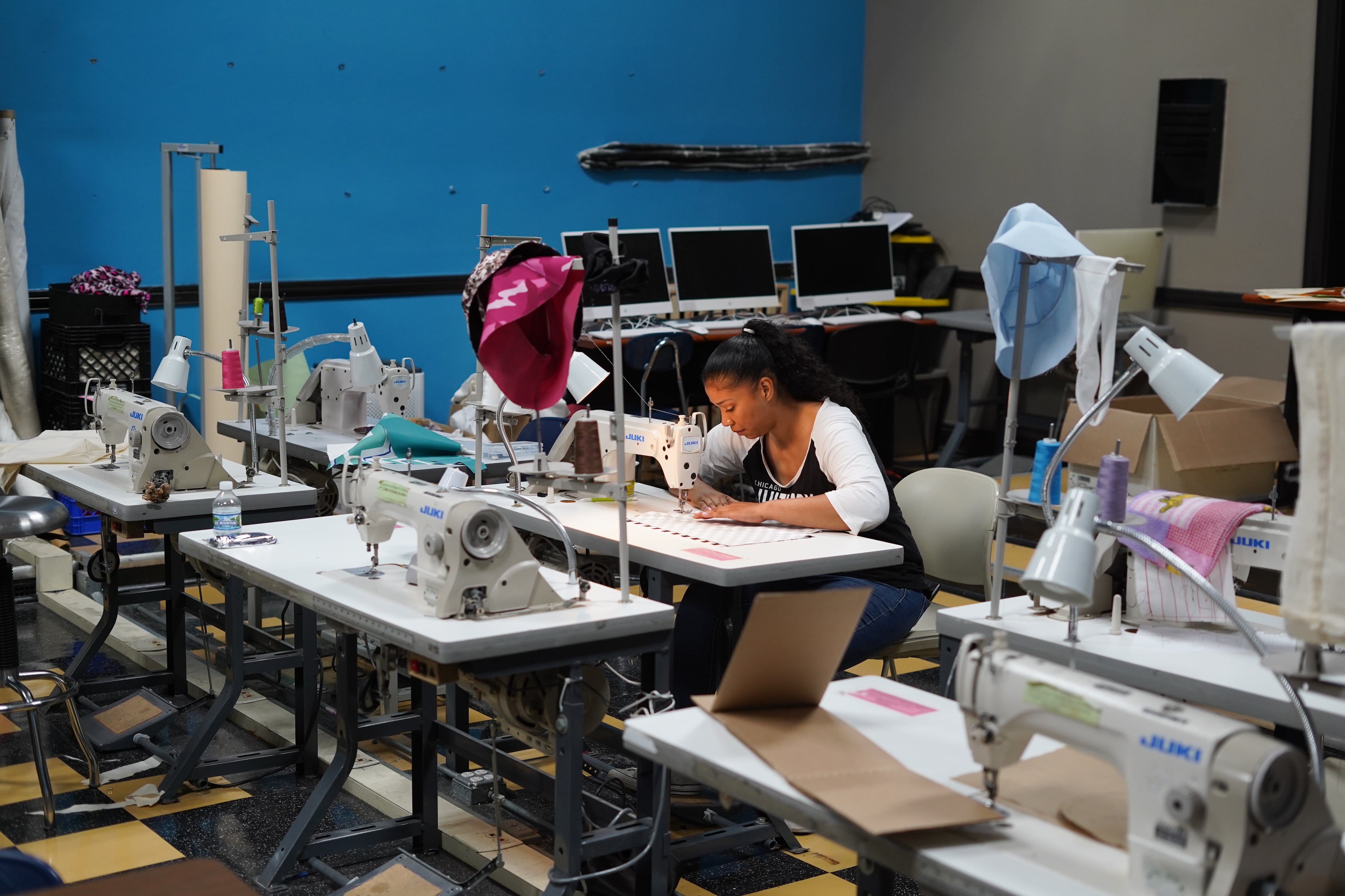 A woman works at a machine in the sewing lab of a school.