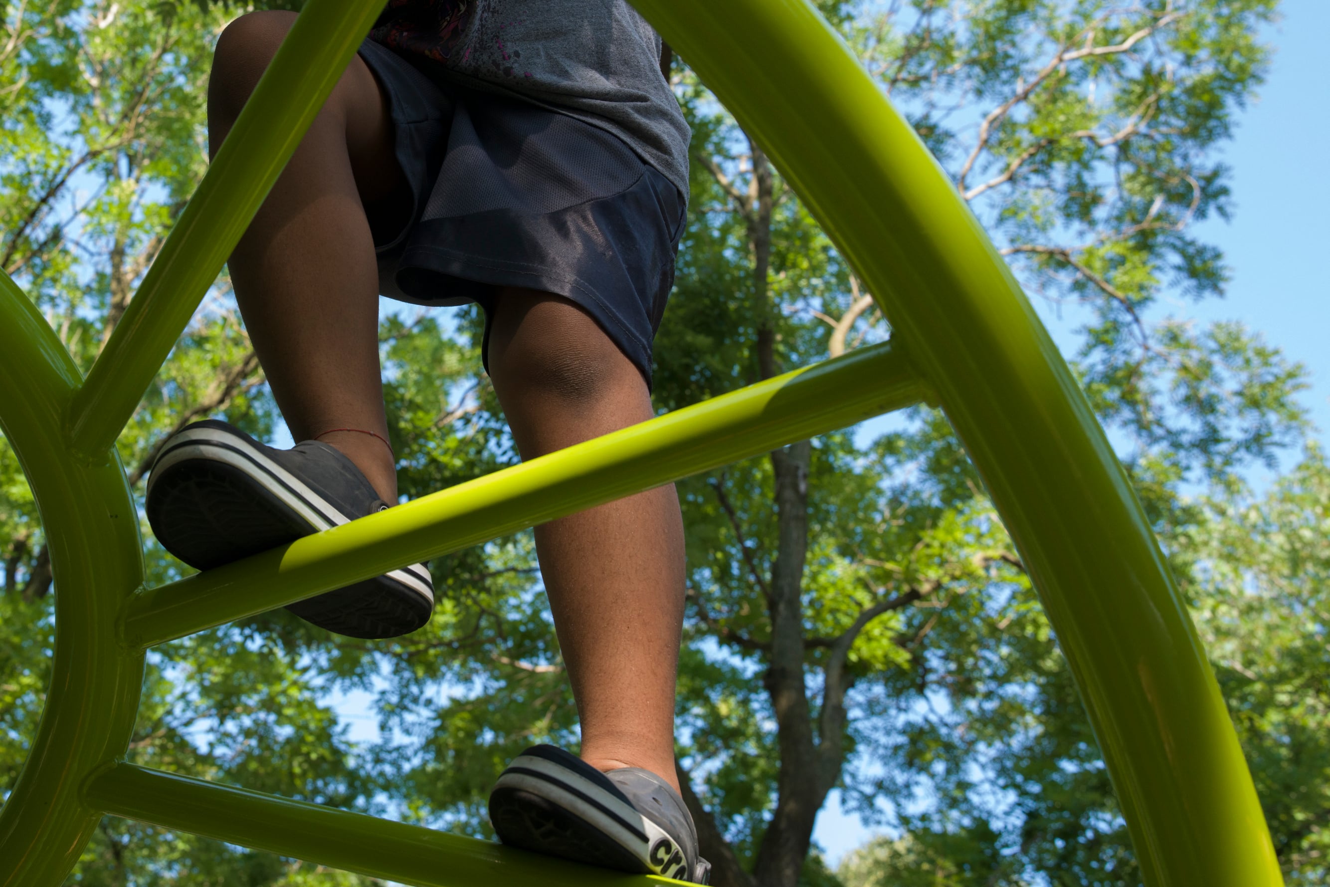 A child is climbing on a green ladder.