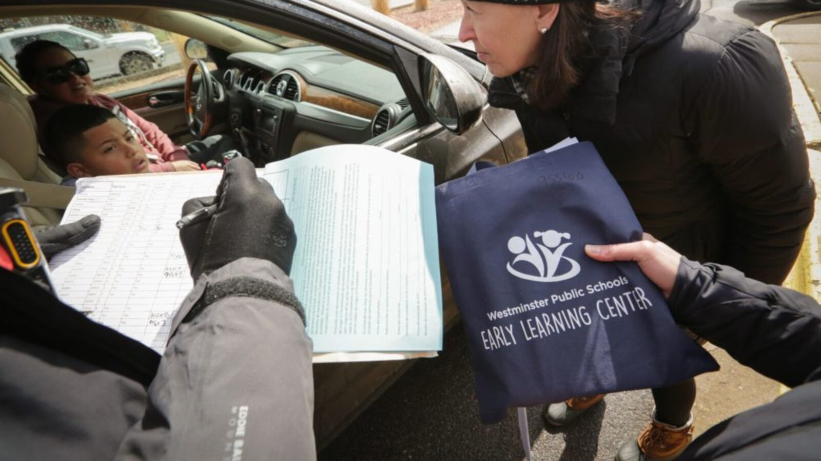 Volunteers from Sherrelwood Elementary School in Westminster hand out laptops and educational materials to parents and students on Friday, March 13, as schools prepare to close for two weeks.
