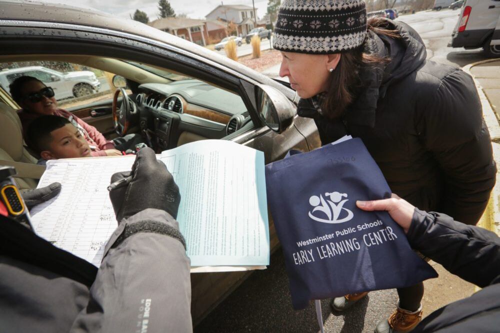 Volunteers from Sherrelwood Elementary School in Westminster hand out laptops and educational materials to parents and students on Friday, March 13, as schools prepare to close for two weeks.