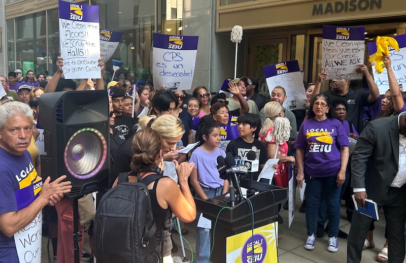 A crowd of people stand with signs.