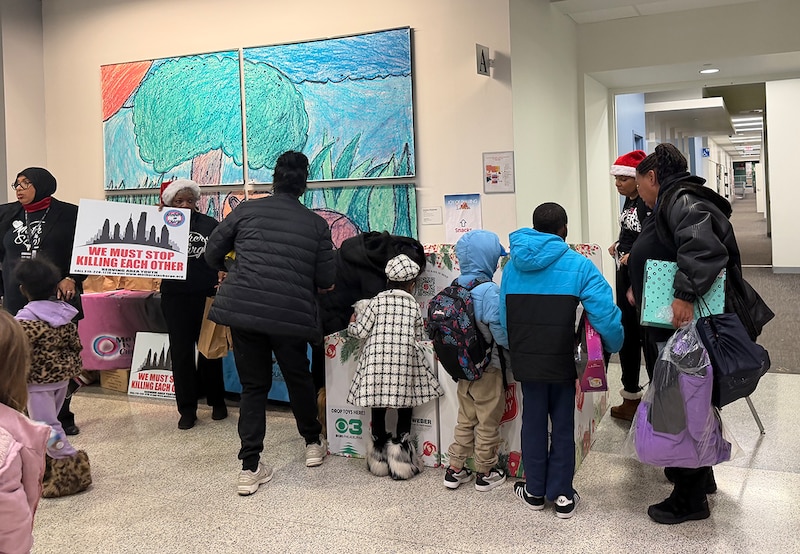 A group of children and adult stand together in front of a giant piece of art