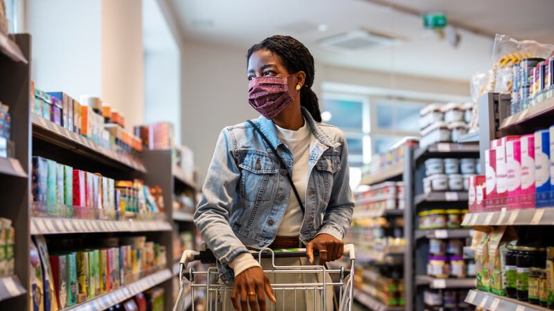 A woman wearing a face mask shops in a grocery store.