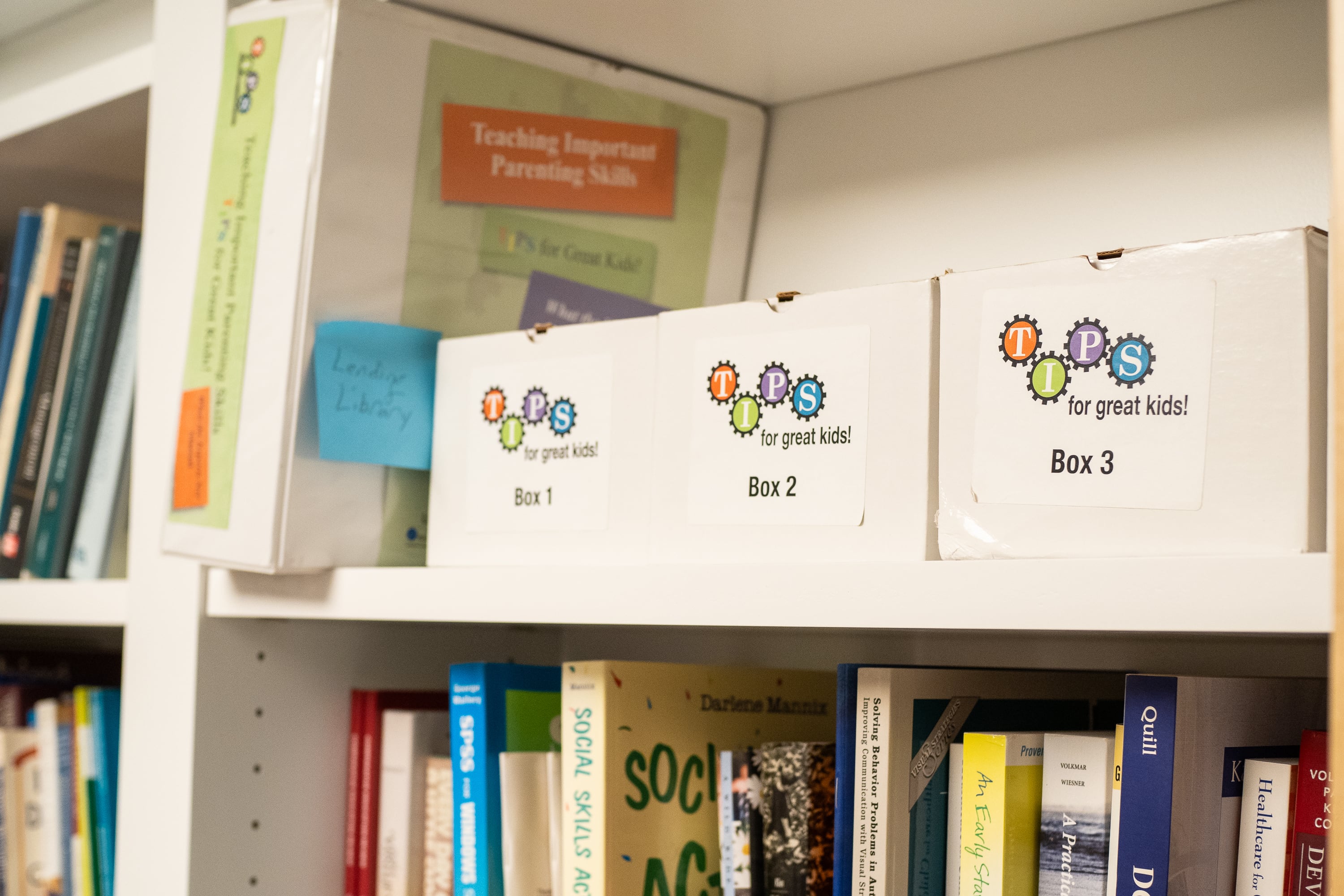 Books and other materials at the Yale Child Study Center children’s library. One binder reads "Teaching Important Parenting Skills" and three boxes have labels that say "TIPS for great kids."