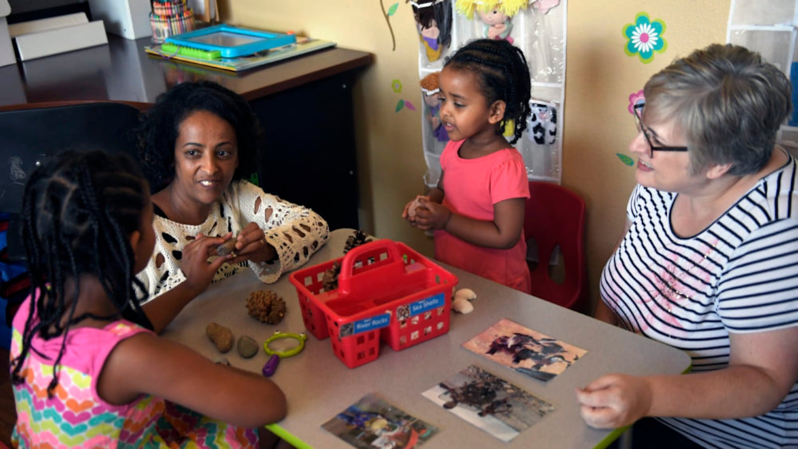 Yemi Habte works with her daughters Charis Mandefro 9, and Anna Mandefro 2, as Stephanie Olson of Aurora, a MyVyllage mentor, watches during a mentoring session in Habte's home.