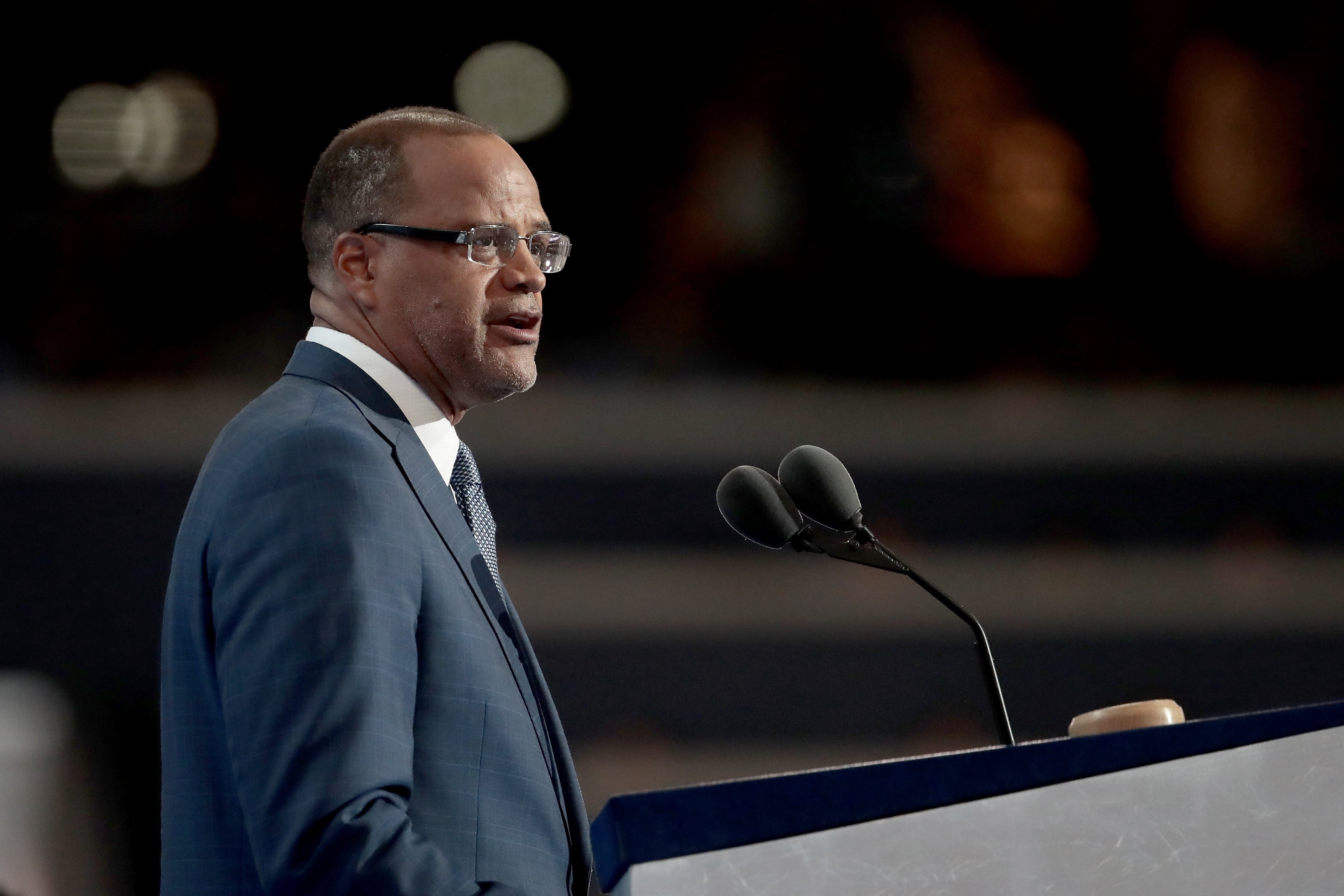 Eagle Academy founder David Banks, wearing a suit and glasses, stands at a podium to speak during a convention.